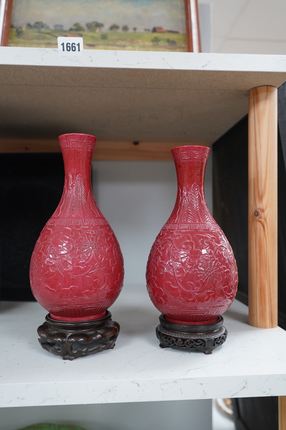 A pair of Chinese ruby ground ‘lotus’ bottle vases, late 19th century, each carved in relief with lotus flowers, scrolling tendrils and leaves, both with carved stands, 24cm high. Condition - one vase the neck broken bot